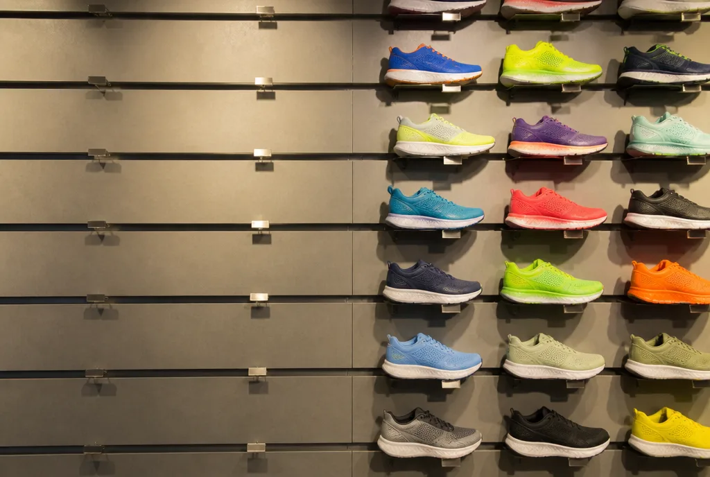 A sports shop running shoe wall, the left half stripped bare and the right half full of colourful shoes