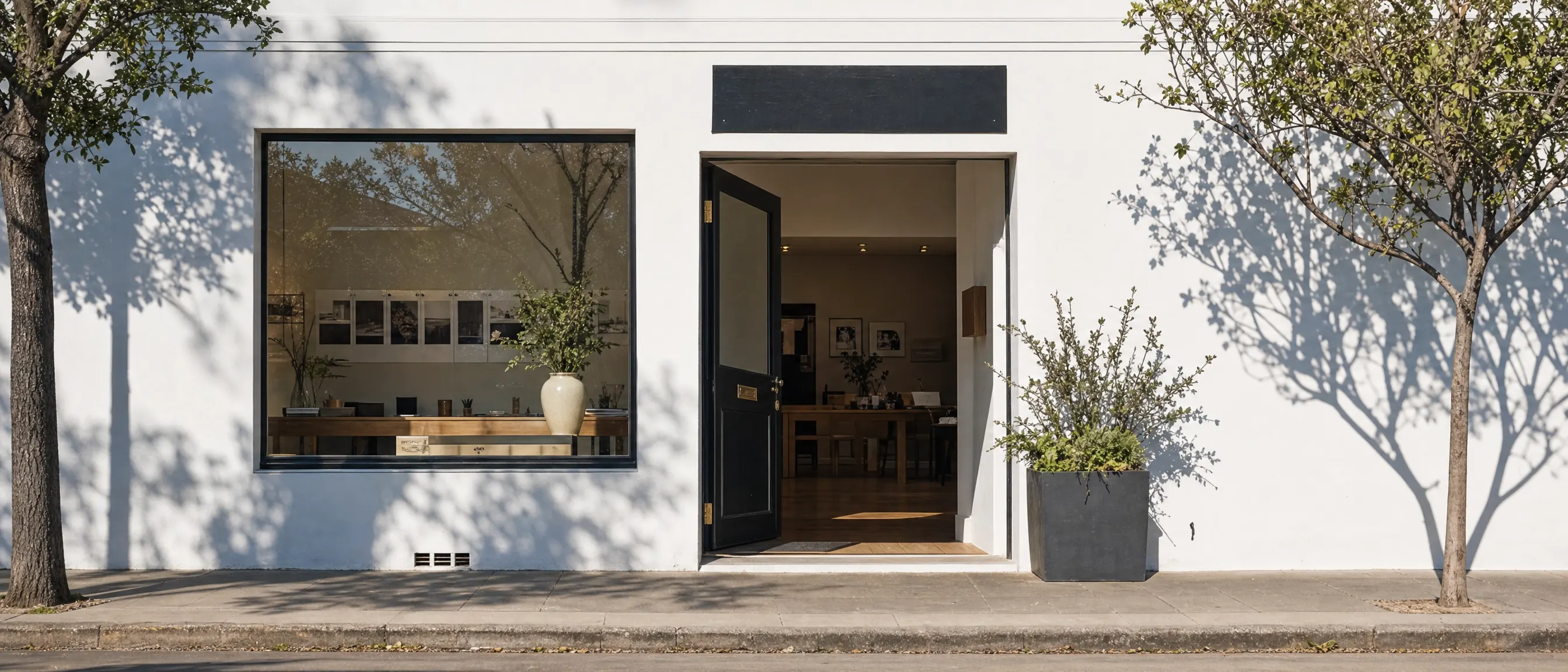 The open front of a small independent shop in afternoon daylight, seen from across a quiet pavement